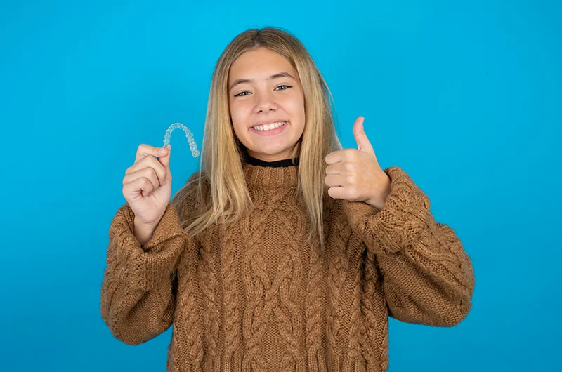teen_holding_clear_aligner